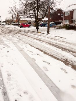 snow covered street road with tire tracks leading through village houses; essex; england; uk
