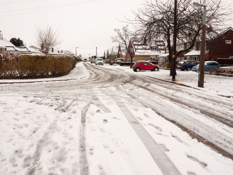 snow covered street road with tire tracks leading through village houses; essex; england; uk