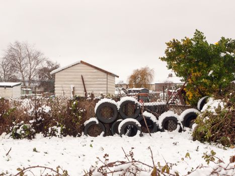 side of allotment scene winter close up snow december stack of tires; essex; england; uk