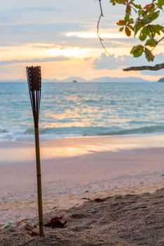 focus on the torch on the sandy beach of Thailand and the sunset on the sea