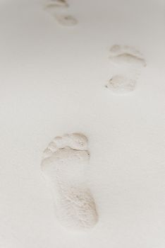 close-up of footprints on white sand on a desert island