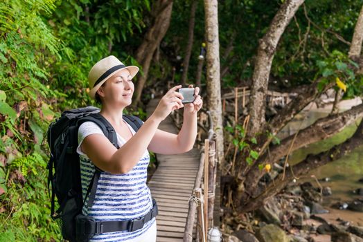 happy tourist on vacation photographs beautiful landscapes on the phone