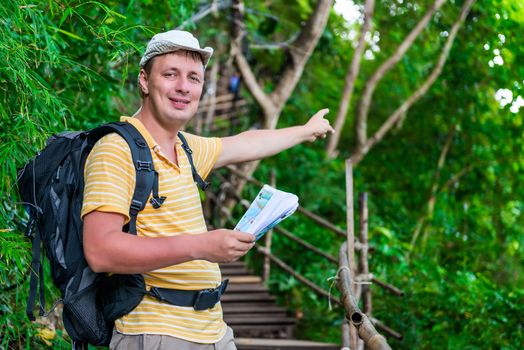 tourist with a backpack in the Asian jungle in the hike shows the direction of the route