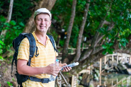 portrait of a happy tourist with a backpack against the backdrop of the jungle in Thailand