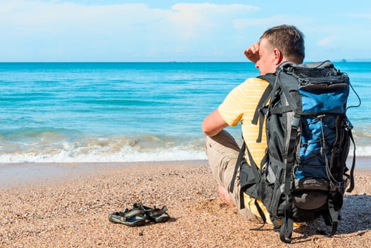 traveler with a backpack resting on the beach near the sea in Thailand