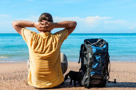 man tourist with a backpack looking at the beautiful calm sea on vacation