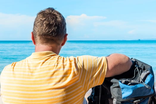 male tourist admires the sea, view from the back