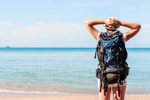 tourist with a backpack admiring the beautiful sea, view from the back