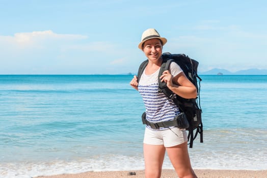 woman tourist with a big backpack on the background of a beautiful sea in Thailand in a hike