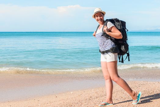 tourist with a backpack walks along the sandy beach of the resort of Thailand on a sunny day