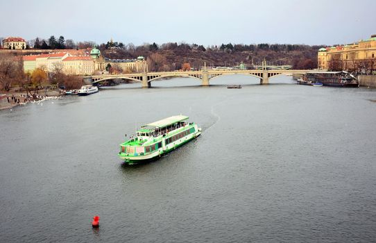 View of the Vltava river with tourist ship and Prague Castle above in old Prague town center.