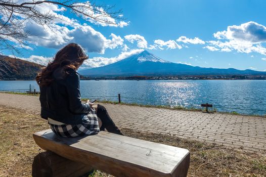 Woman sitting on a bench at kawaguchiko lake, Japan. View of fuji mountains.