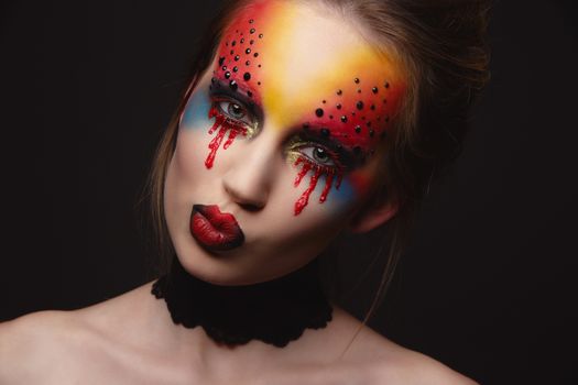 Portrait of young and beauty female model with creative makeup, bloody eyes and black rhinestones