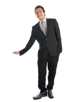 Full body portrait of young Southeast Asian businessman hand leaning on invisible object, standing isolated on white background. 