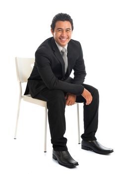 Full body attractive young Southeast Asian businessman sitting on chair, isolated on white background. Asian malay male model.