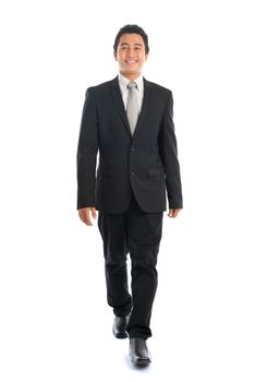 Full body front view portrait of attractive young Southeast Asian businessman walking, isolated on white background. 