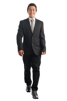 Full body front view portrait of handsome young Southeast Asian businessman walking, isolated on white background. 