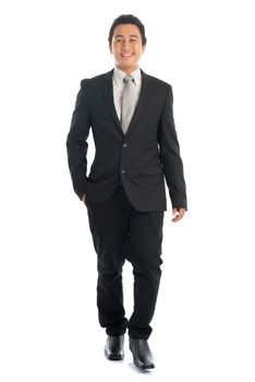 Full length front view portrait of attractive young Southeast Asian businessman walking, isolated on white background. 
