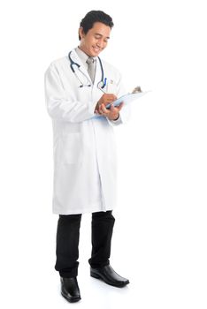 Full length attractive young male Southeast Asian medical doctor writing, standing isolated on white background.