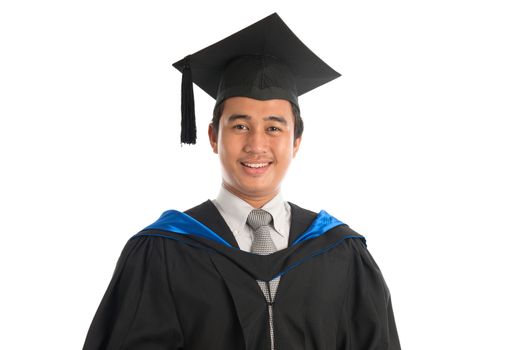 Portrait of attractive Southeast Asian male university student in graduation gown smiling, standing isolated on white background. 