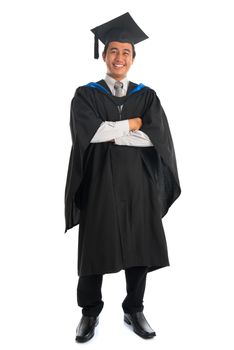 Full body happy arms crossed Asian male university student in graduation gown smiling, isolated on white background. Good looking Southeast model.