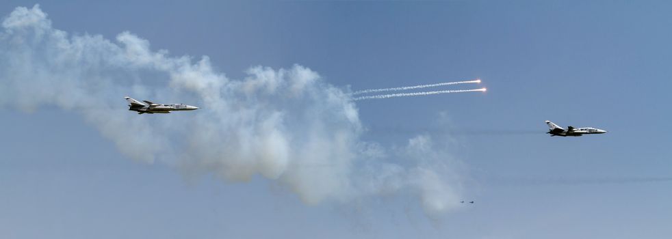 Aircraft fighter flies and shoots heat guns in the blue sky...