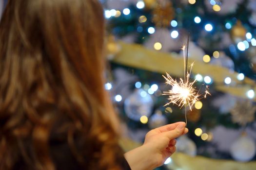 Teen girl holding sparklers and christmas background
