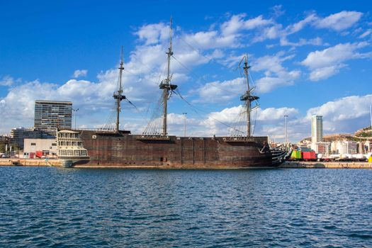 View on big old wooden vessel in marina on Mediterranean sea coast in Spain Alicante