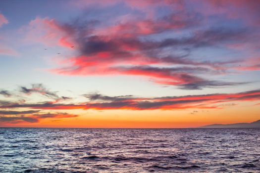 Sunset sunrise in open sea with dramatic cloudy calm clear sky