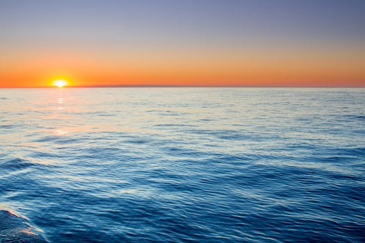 Sunset sunrise in open sea with dramatic cloudy calm clear sky