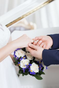 Wedding day. The groom places the ring on the bride's hand.