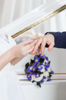 Wedding day. The groom places the ring on the bride's hand.