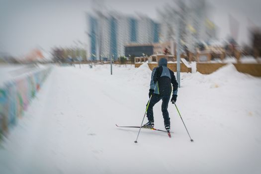 young man skiing in a black jacket along the river