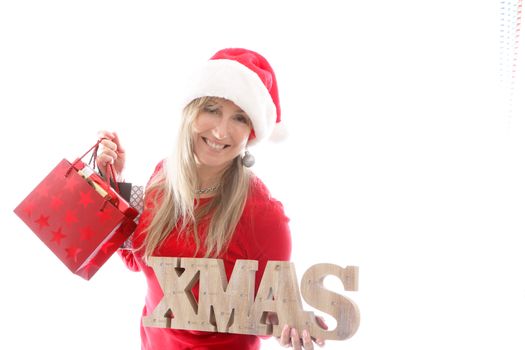 A smiling cheerful woman holding xmas sign and shopping bags, 