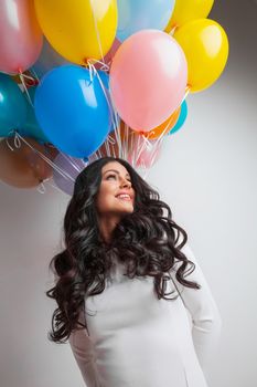 Cheerful woman holding many colorful balloons, celebration and happiness concept