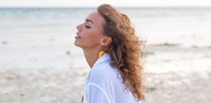 Attractive woman enjoy sea scent smelling wind with closed eyes on sea beach