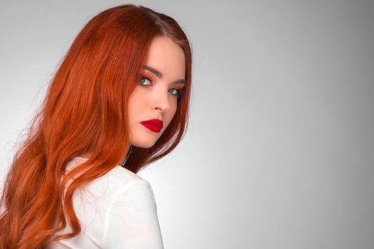 Gorgeous redhead girl with wavy hair beauty studio portrait