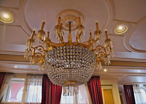 Beautiful huge, richly decorated chandelier on ceiling