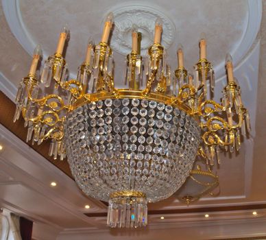 Beautiful huge, richly decorated chandelier on ceiling