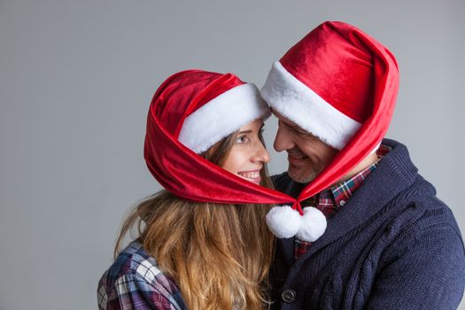 Happy smiling couple in Santa hats on gray background