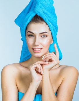 Beautiful woman with towel on head applying creme after shower