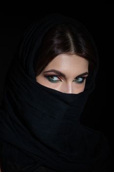 Beautiful muslim woman in niqab traditional veil against on dark background