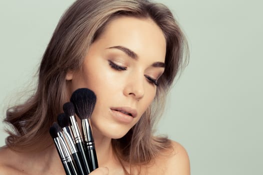 Portrait of beauty girl with makeup brushes set