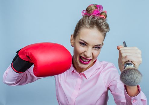 Fighting for beauty concept, funny woman with in boxing glove holding make-up brush