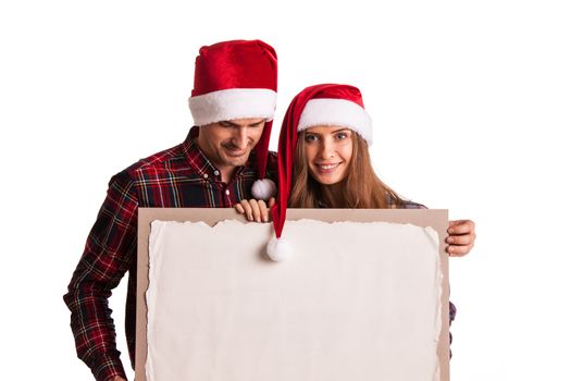 Happy couple in Santa hats holding blank banner with copy space