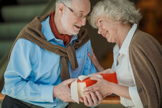 Senior couple in shopping mall with gifts