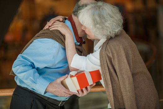 Senior couple in shopping mall with gifts