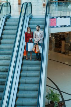 Happy beautiful young couple with shopping bags in mall