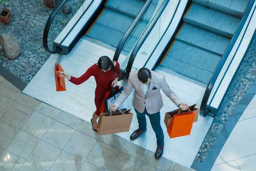 Happy beautiful young couple with shopping bags in mall