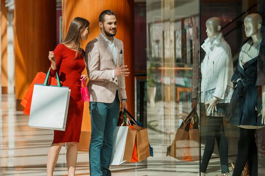 Happy beautiful young couple with shopping bags in mall